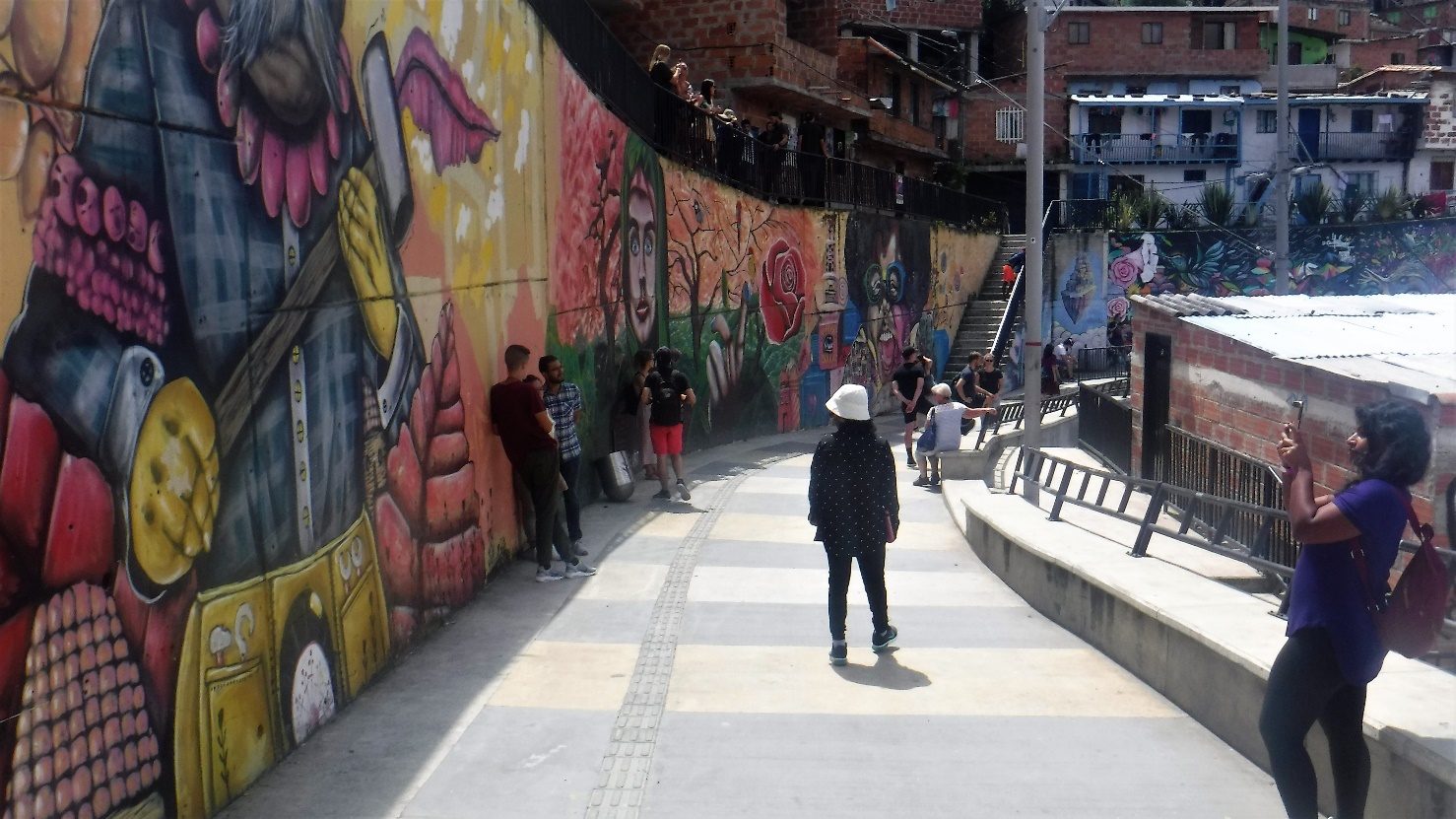 A group of people walking on a sidewalk Description automatically generated