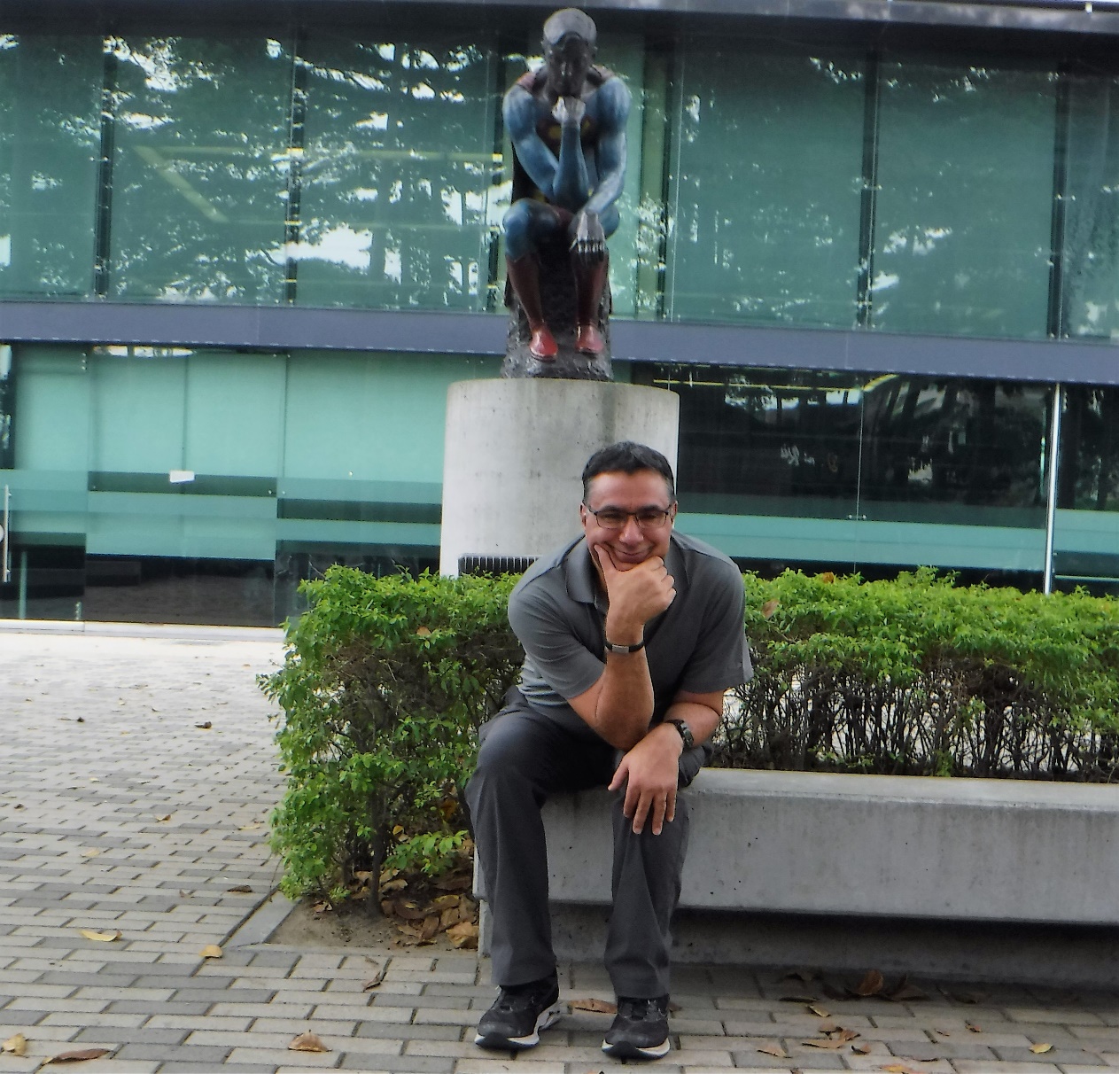 A person sitting on a bench in front of a building Description automatically generated