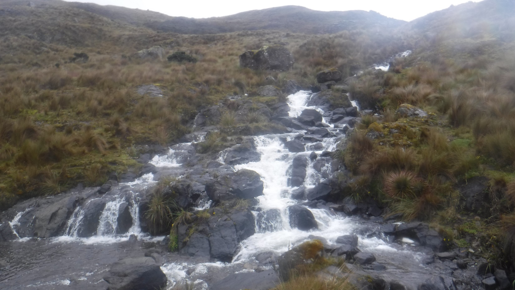 A waterfall with a mountain in the background Description automatically generated