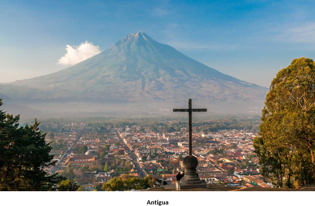 A cross on a stone structure with a mountain in the background Description automatically generated