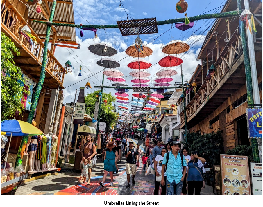 A group of people walking down a street with umbrellas above them Description automatically generated