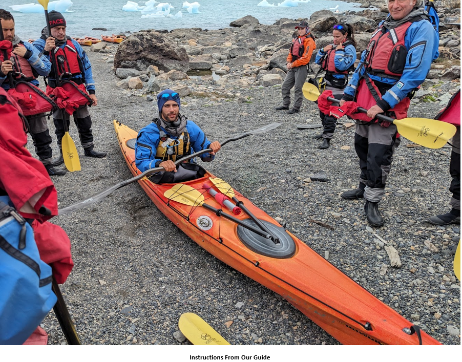 A group of people in kayaks on a rocky beach Description automatically generated