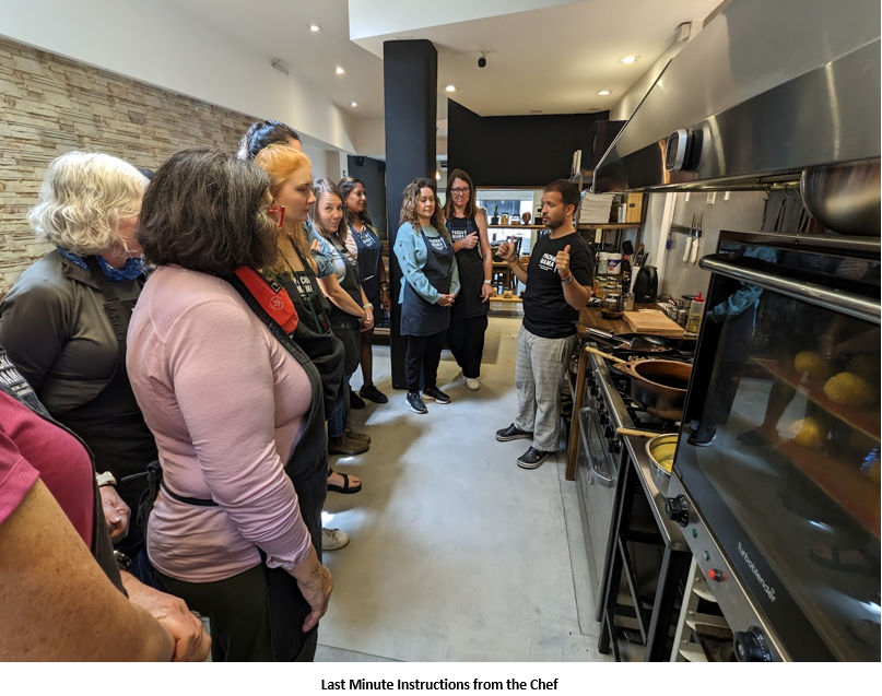 A group of people standing in a kitchen Description automatically generated
