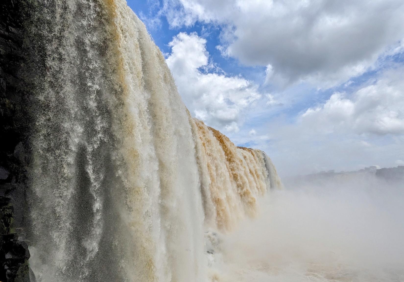 A large waterfall with clouds in the sky Description automatically generated