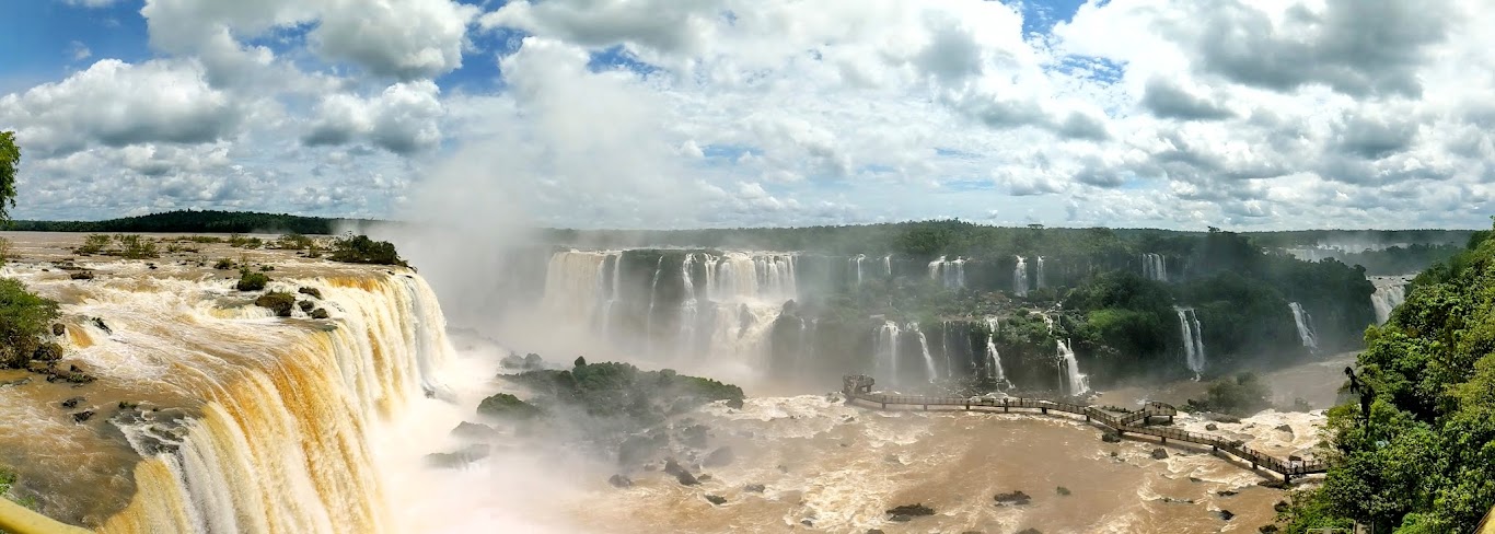 A large waterfall with clouds in the sky with Iguazu Falls in the background Description automatically generated