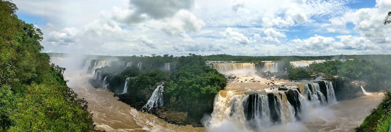 A waterfall with trees and clouds Description automatically generated