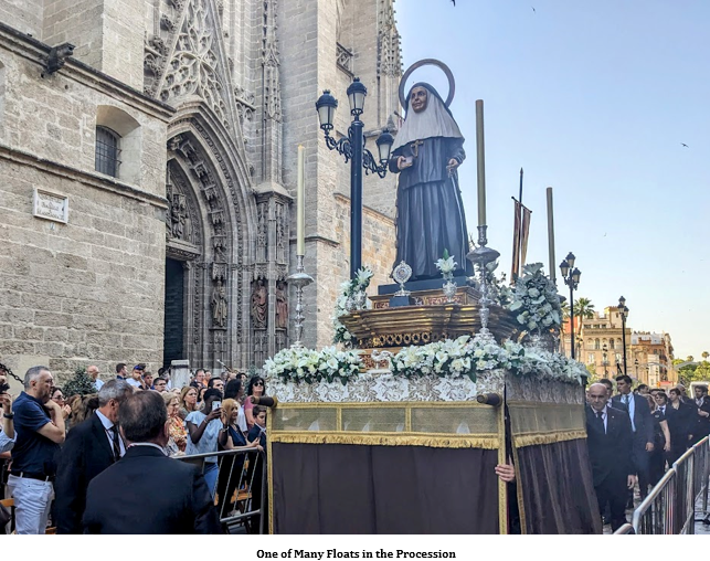 A statue of a nun on a podium with a crowd of people Description automatically generated